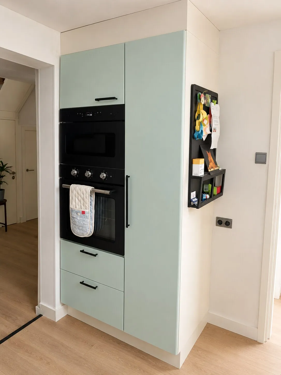Hoge kastenwand in mintgroen met inbouwmagnetron en memobord