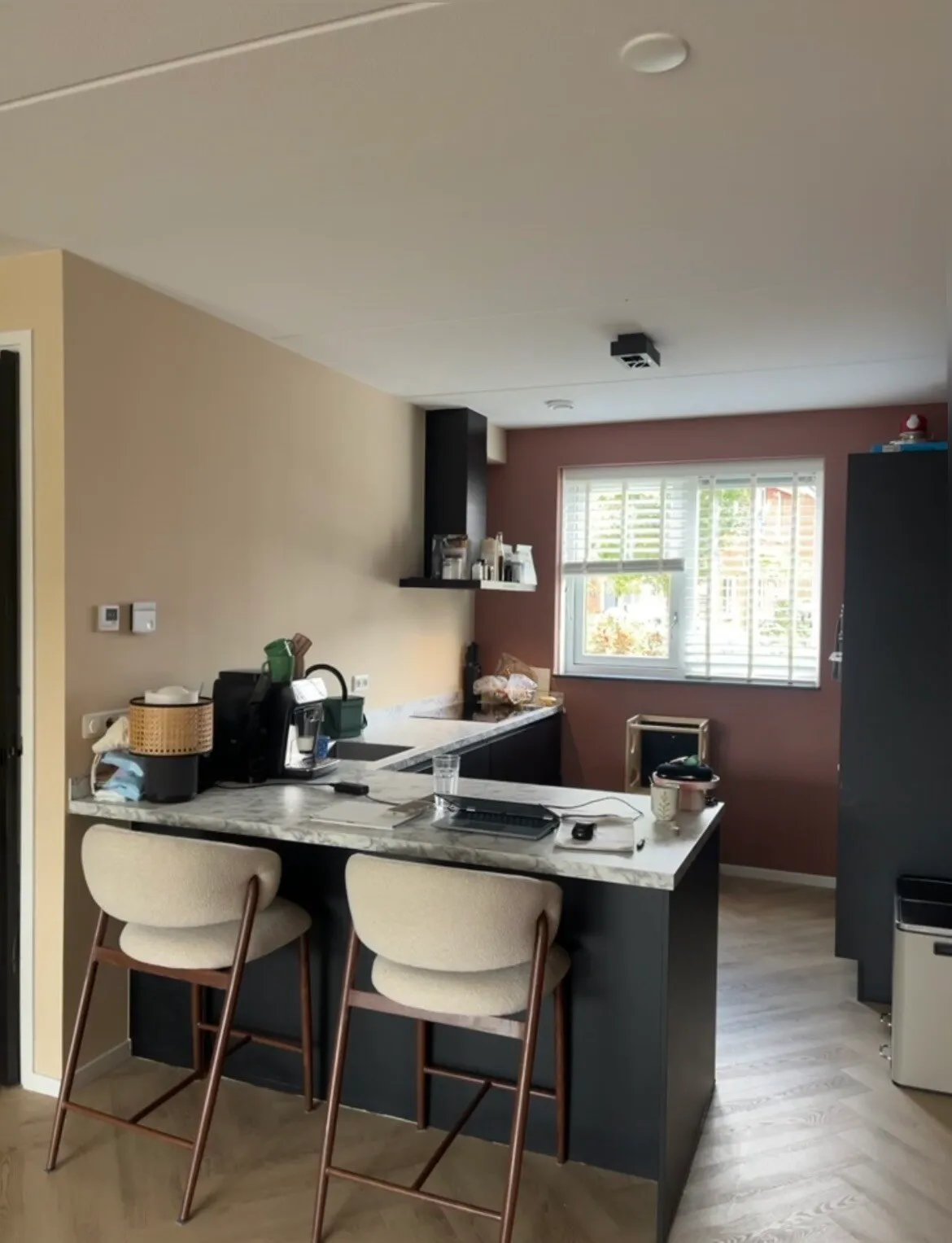 Open keuken met warme roodbruine accentwand achter het raam